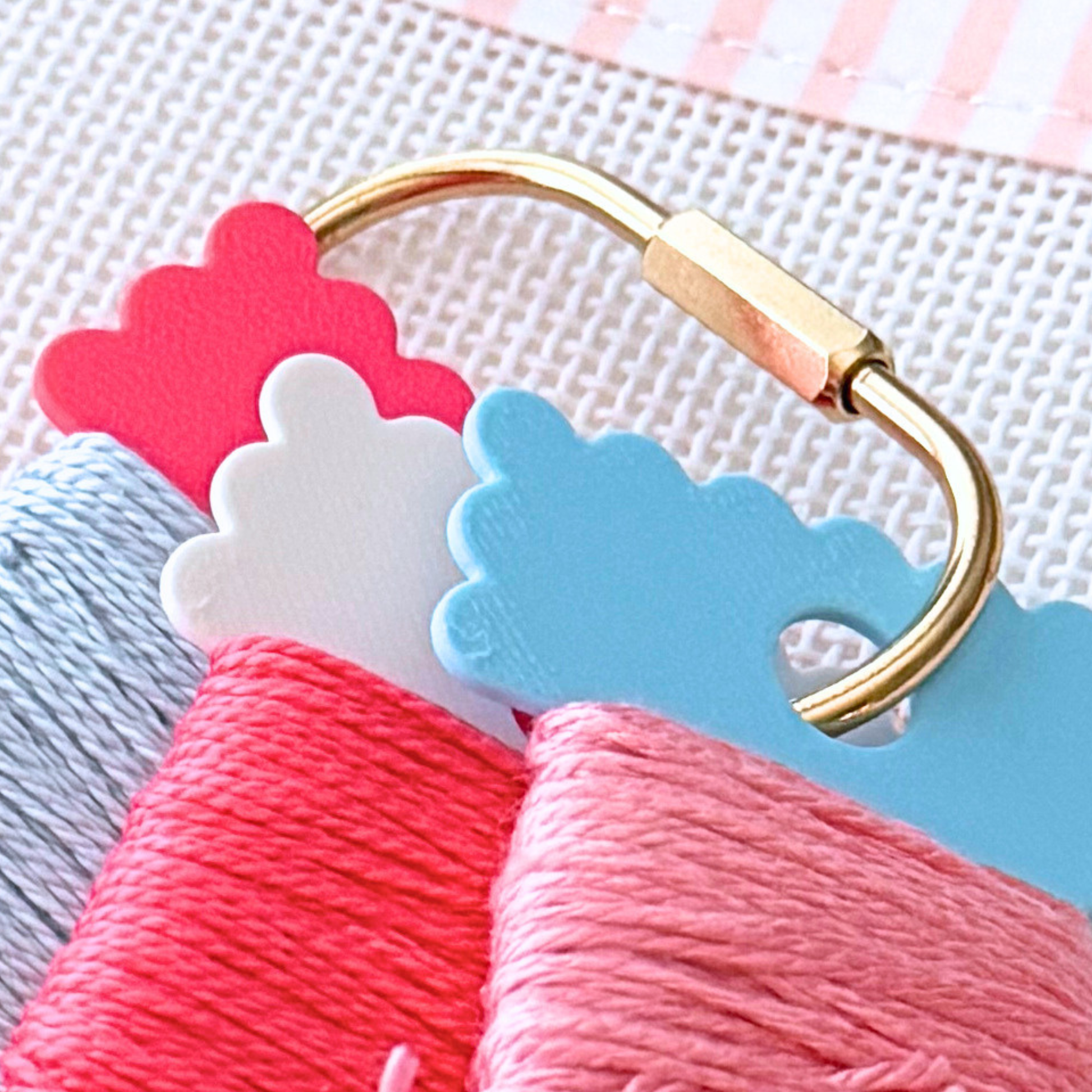 Gold brass project ring holding colorful scallop floss drops for needlepoint organization.